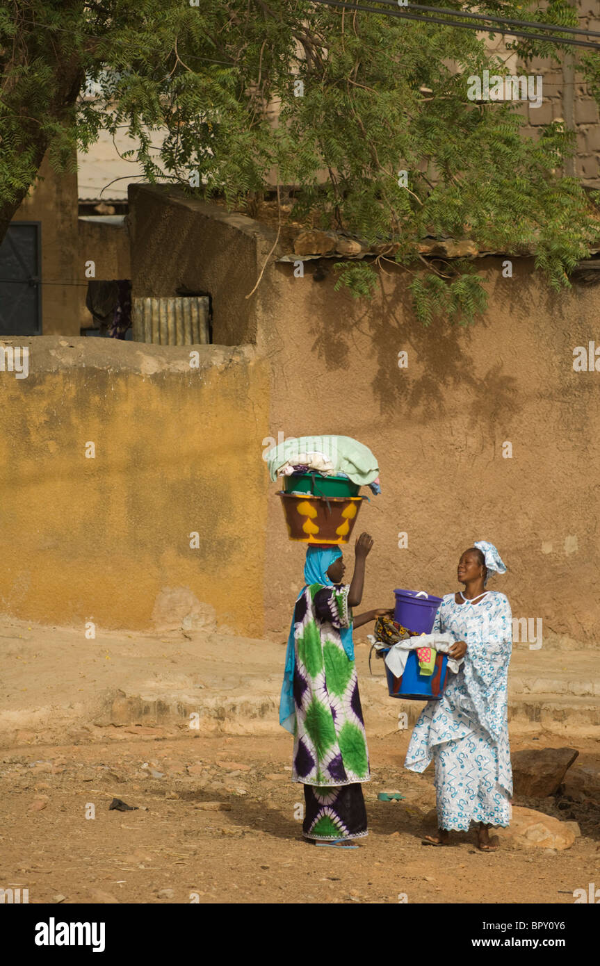 Des femmes portant de blanchisserie le fleuve Sénégal, scène de rue, Bakel, Sénégal Banque D'Images