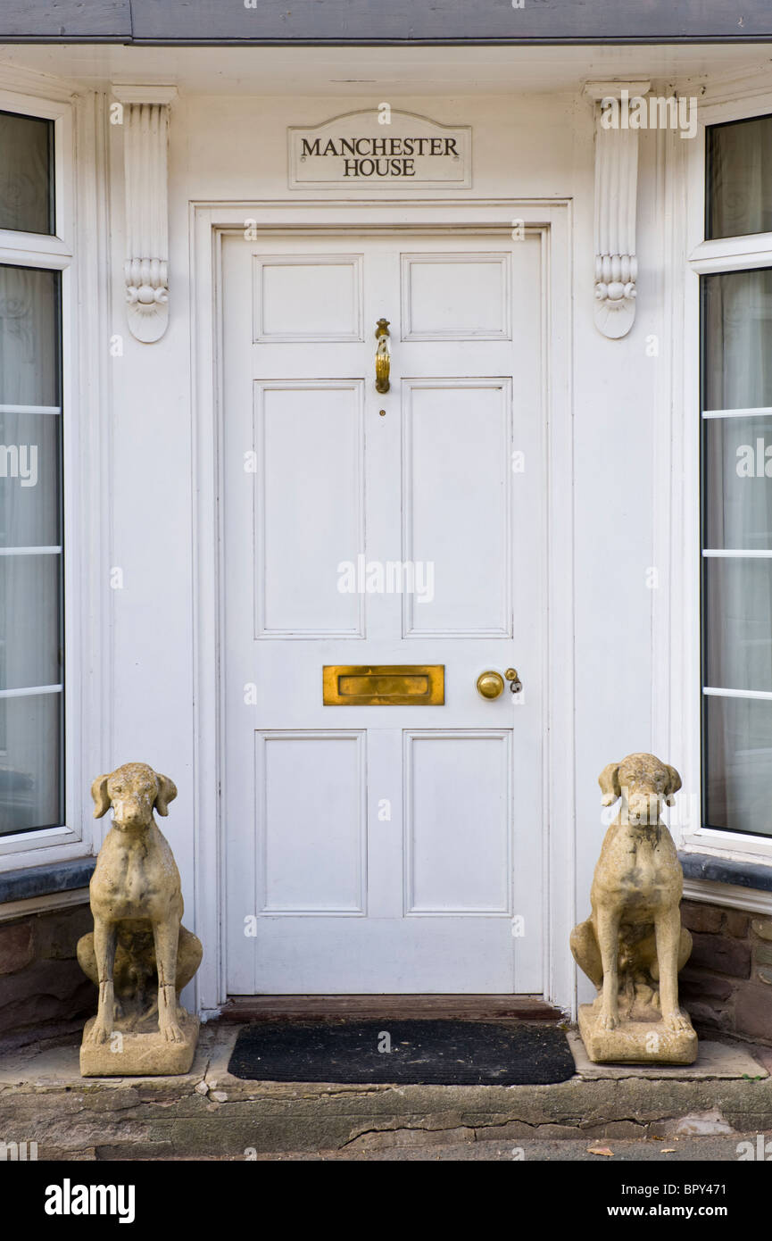 Panneaux en bois peint en blanc, porte d'entrée de maison avec le bouton  laiton heurtoir letterbox et pierre hound chiens assis à l'extérieur Photo  Stock - Alamy