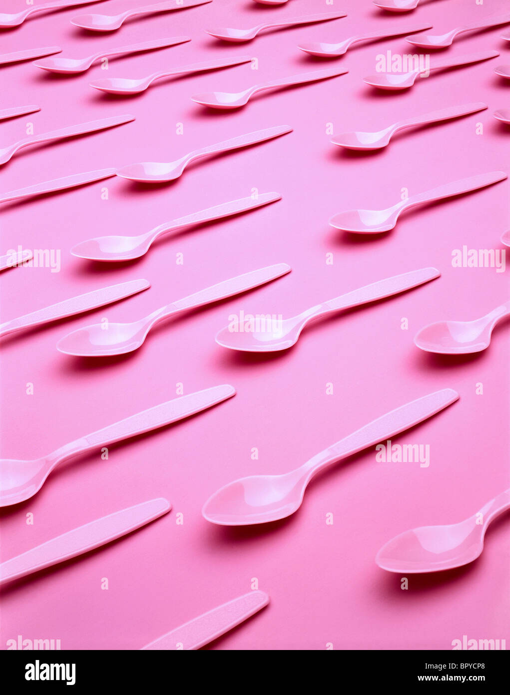 Cuillères en plastique rose sur fond rose Banque D'Images