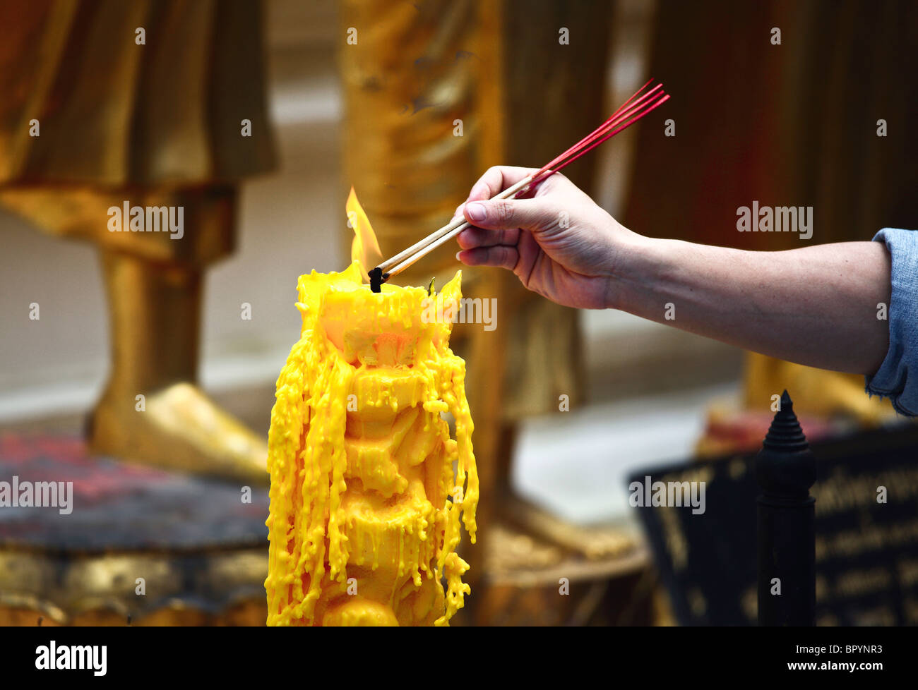 Flamme de bougie jaune, les gens prient dans temple thaïlandais Banque D'Images