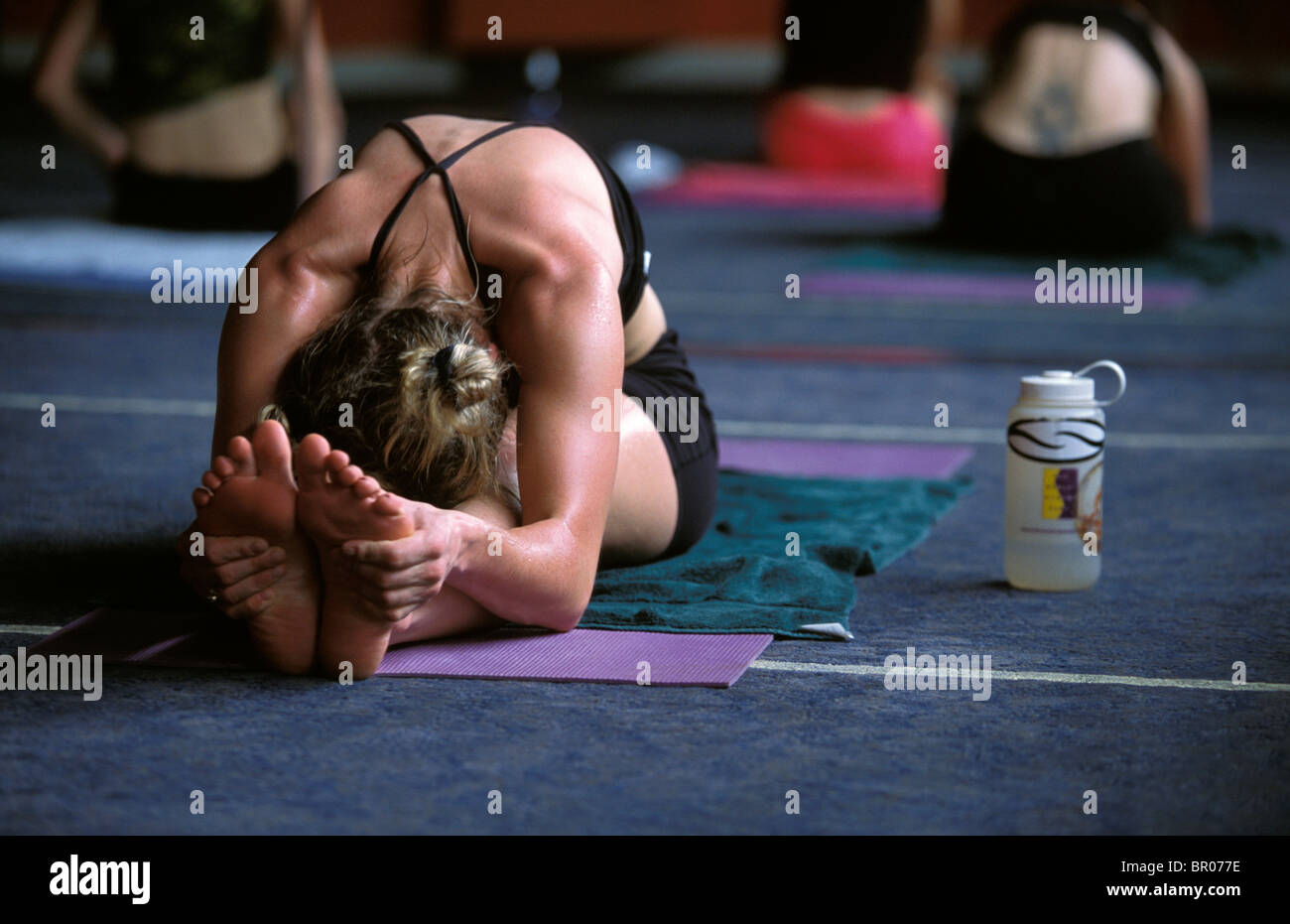 Une athlète féminine s'étendant dans une classe de yoga. Banque D'Images