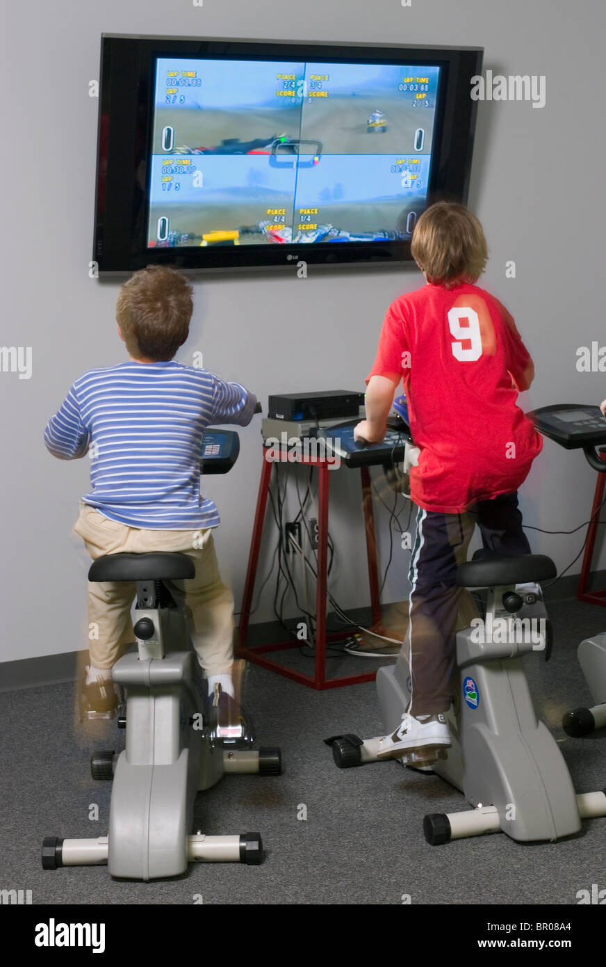 Les enfants à exercer sur les vélos connecté à la télévision. Banque D'Images