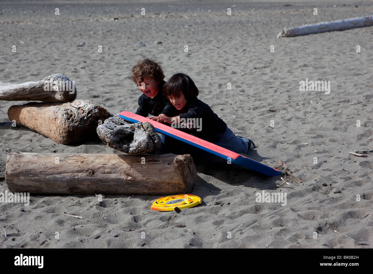 Deux jeunes garçons jouant sur la plage de sciage dans le Pacifique Nord-Ouest Banque D'Images