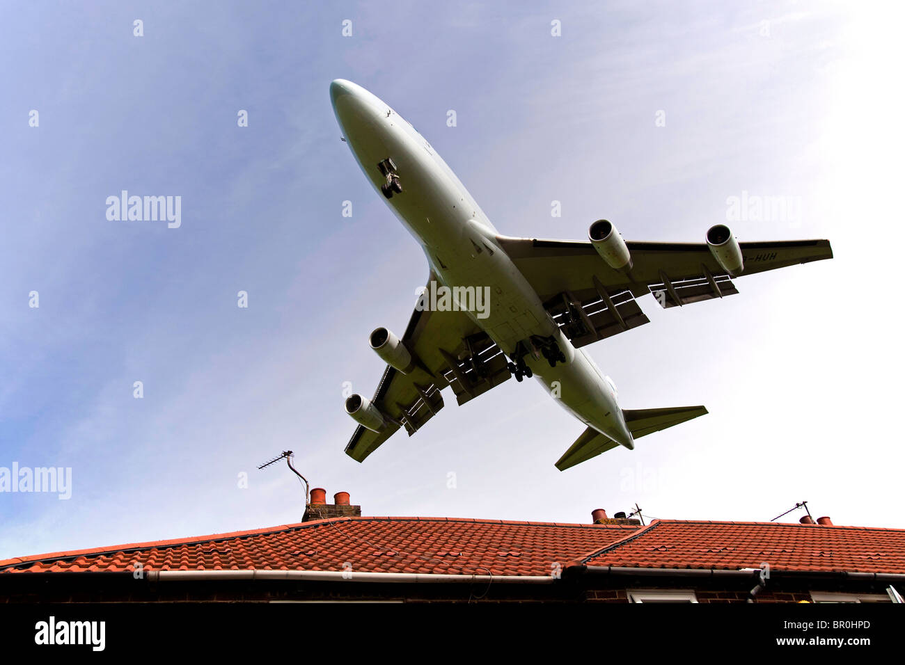 L'atterrissage d'un Boeing 747 jumbo jet au-dessus des toits de la maison à l'extrémité de la piste à l'aéroport de Manchester. Banque D'Images