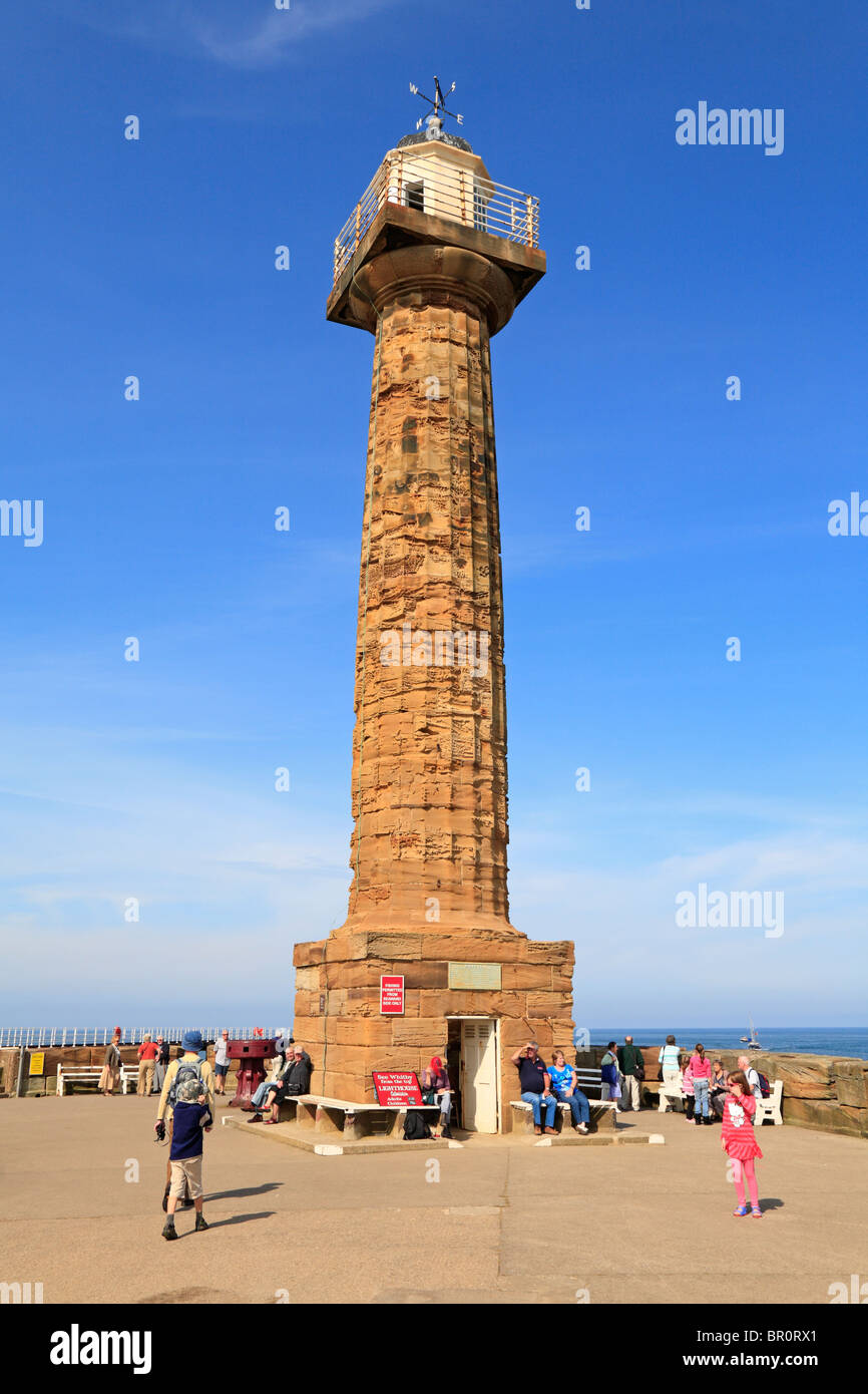 Les touristes par l'ancienne jetée Ouest phare, Whitby, North Yorkshire, Angleterre, Royaume-Uni. Banque D'Images