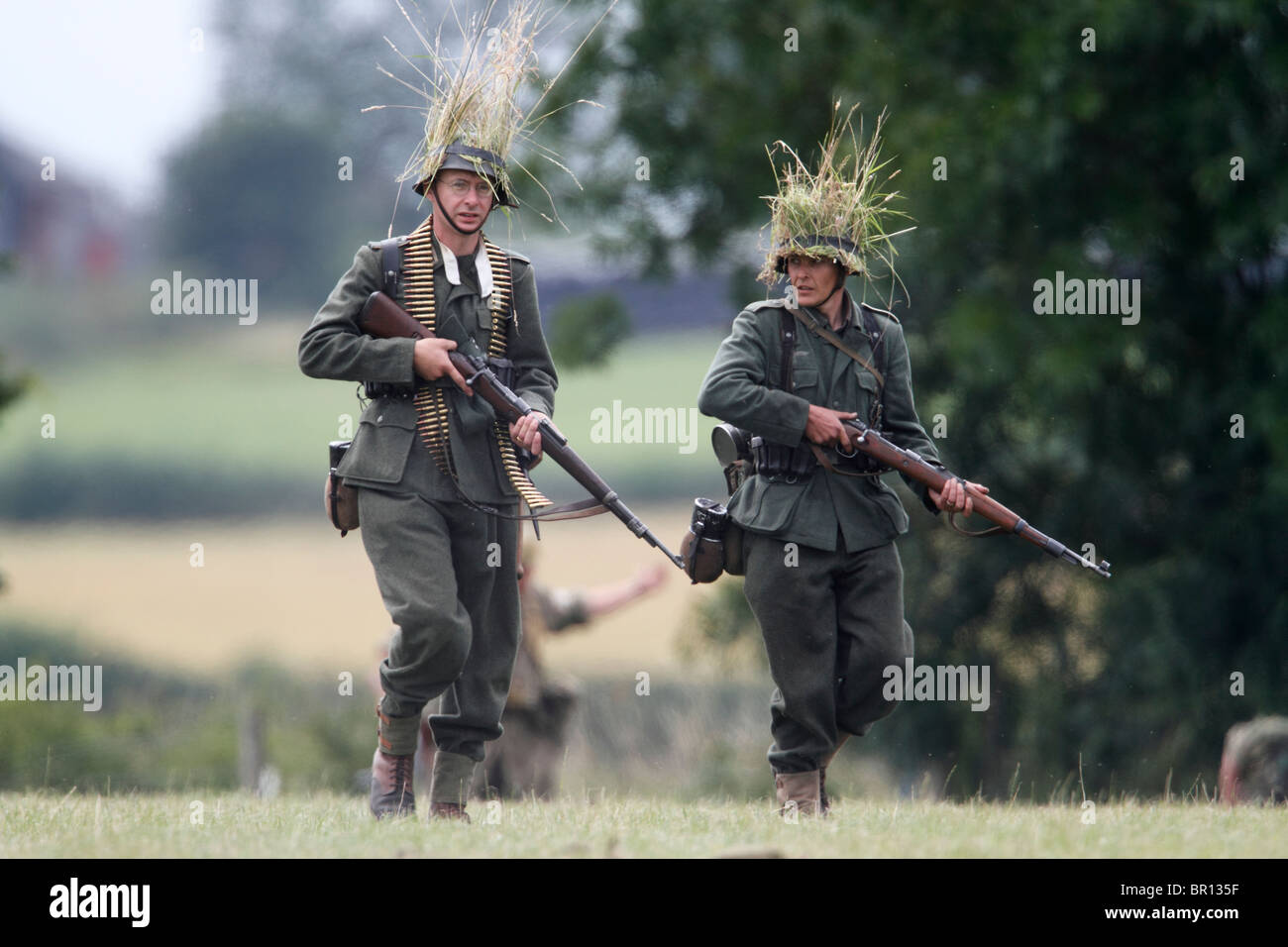La DEUXIÈME GUERRE MONDIALE, les adopter de nouveau. L'infanterie allemande (Schutzen). Le port M40 Domaine tunique, Feldbluse, et un pantalon gris-champ, Feldhosen. Les deux portent le casque standard, M1935 , Stahlhelme avec filet de camouflage. Armé d'une carabine Mauser 98 K 0,3 pouce (7,92 mm) Festival de l'histoire 2010, Kelmarsh Hall, le Northamptonshire. Re-anactors revivez l'histoire de l'Angleterre de l'époque romaine à la Seconde Guerre mondiale Banque D'Images