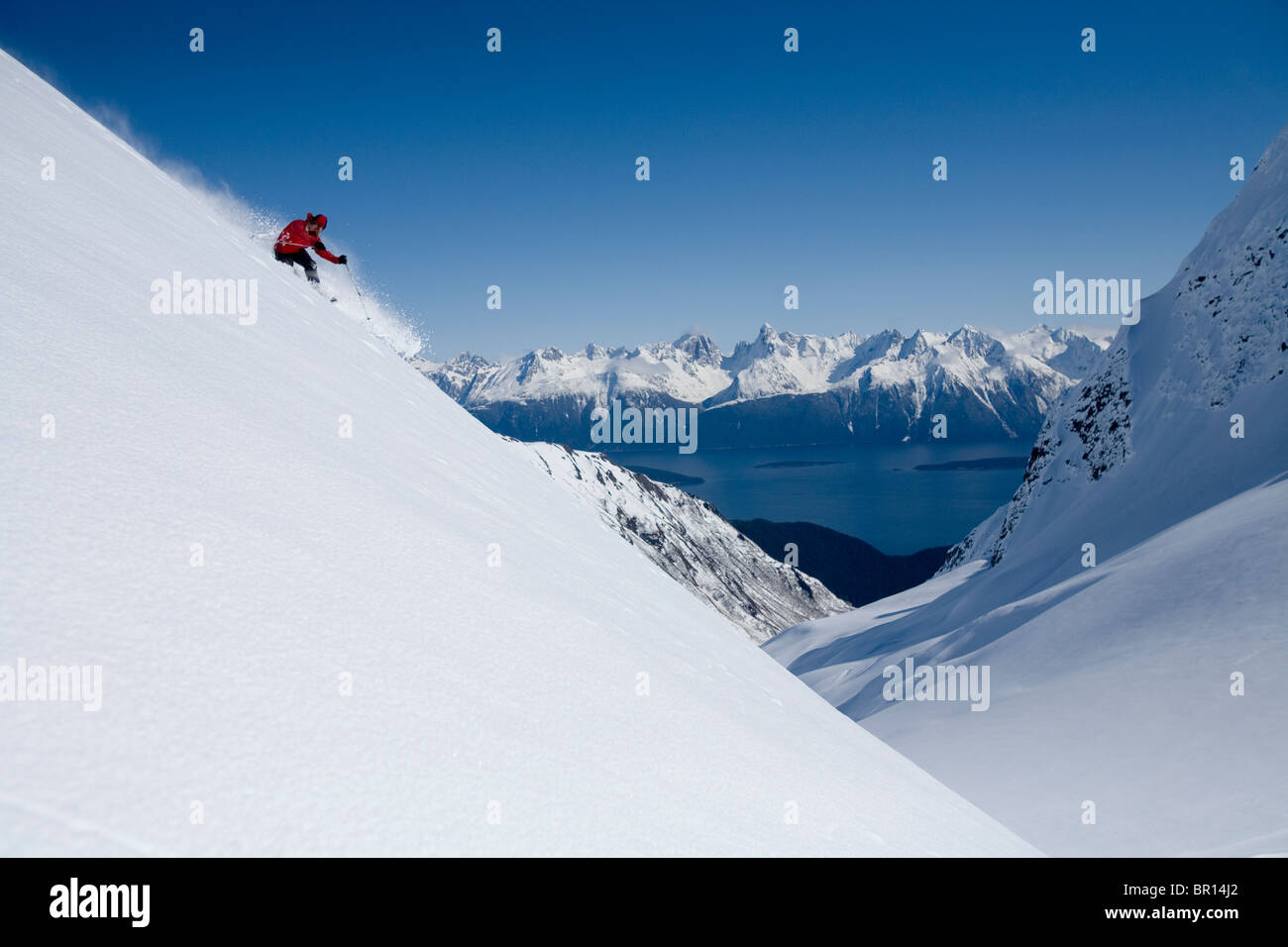 Skieur de télémark ski de montagne escarpé sur ciel bleu ensoleillé jour dans l'arrière-pays de l'Alaska. Banque D'Images