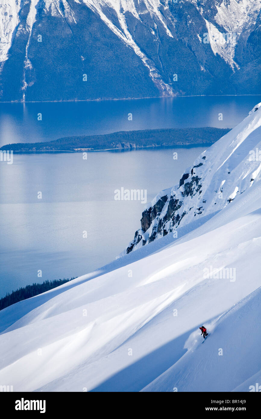 Skieur de télémark descend dans l'arrière-pays de montagnes escarpées du sud-est de l'Alaska. Banque D'Images