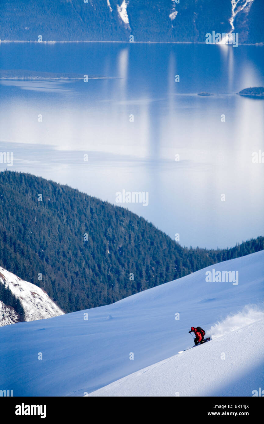 Skieur de télémark descend dans l'arrière-pays de montagnes escarpées du sud-est de l'Alaska. Banque D'Images