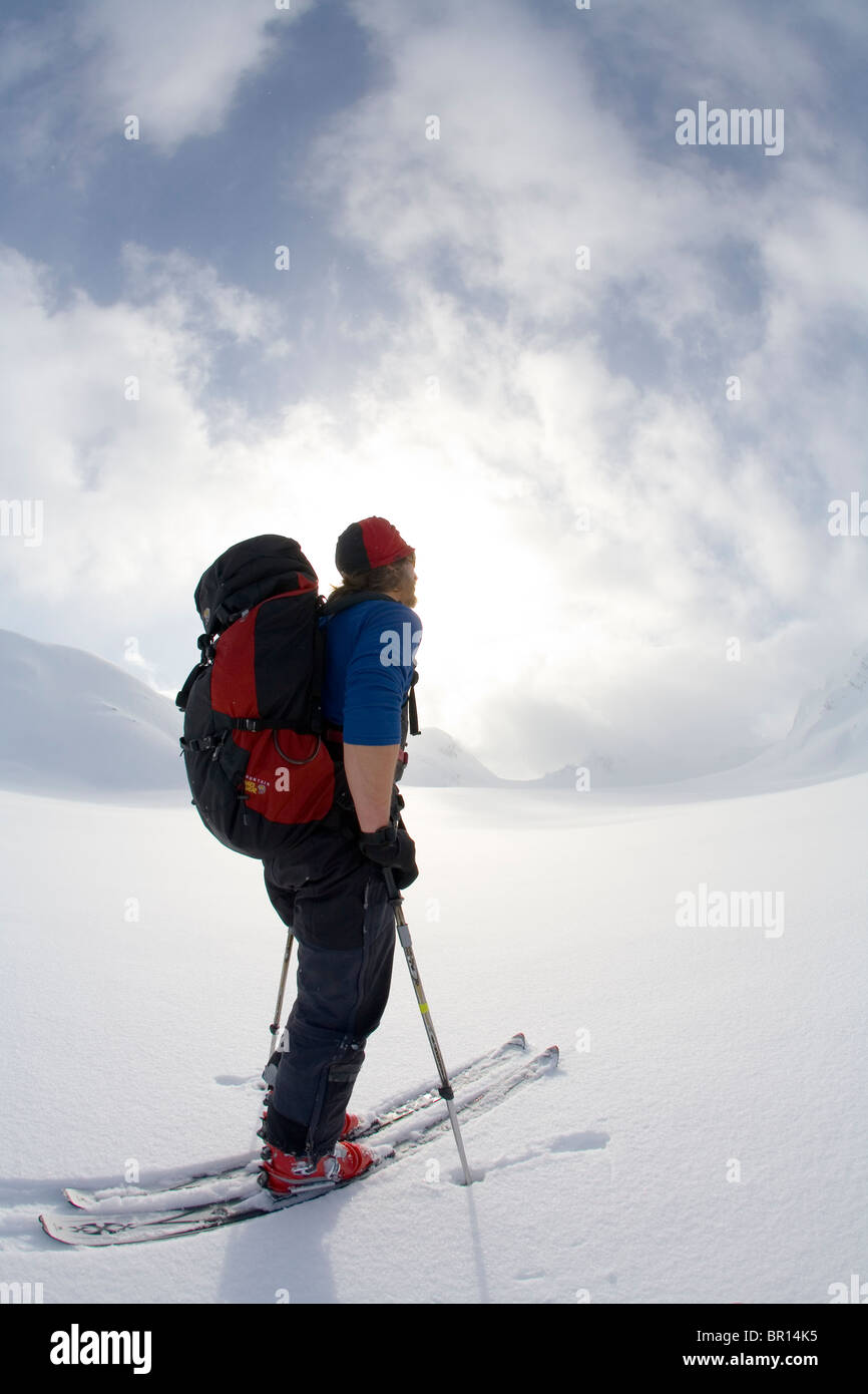 La skieuse de l'arrière-pays traverse sous feu glacier jour ciel d'orage. Banque D'Images