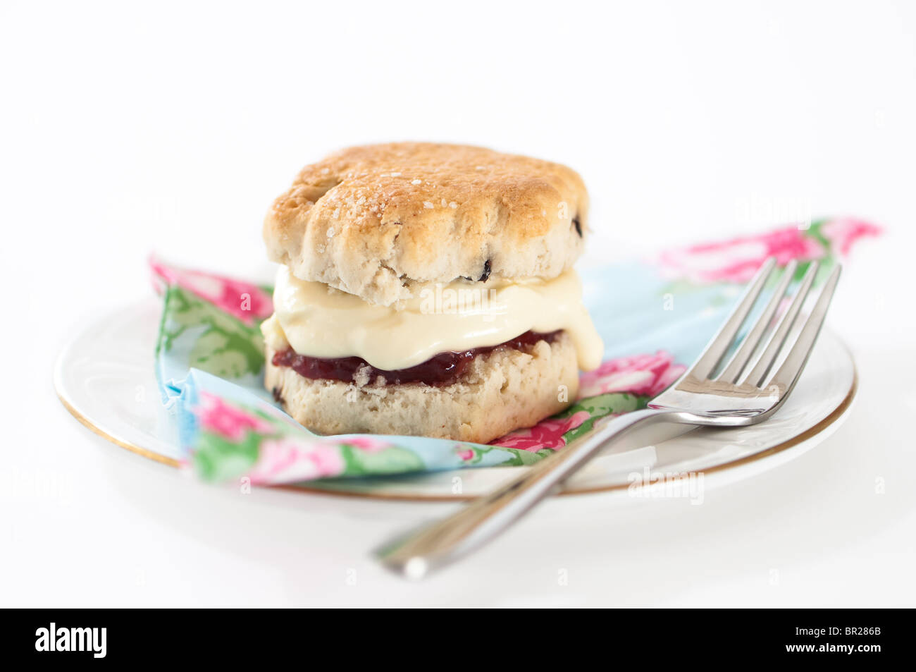 Seul scone avec de la crème et de la confiture de fraise sur la plaque de remplissage avec la fourchette Banque D'Images