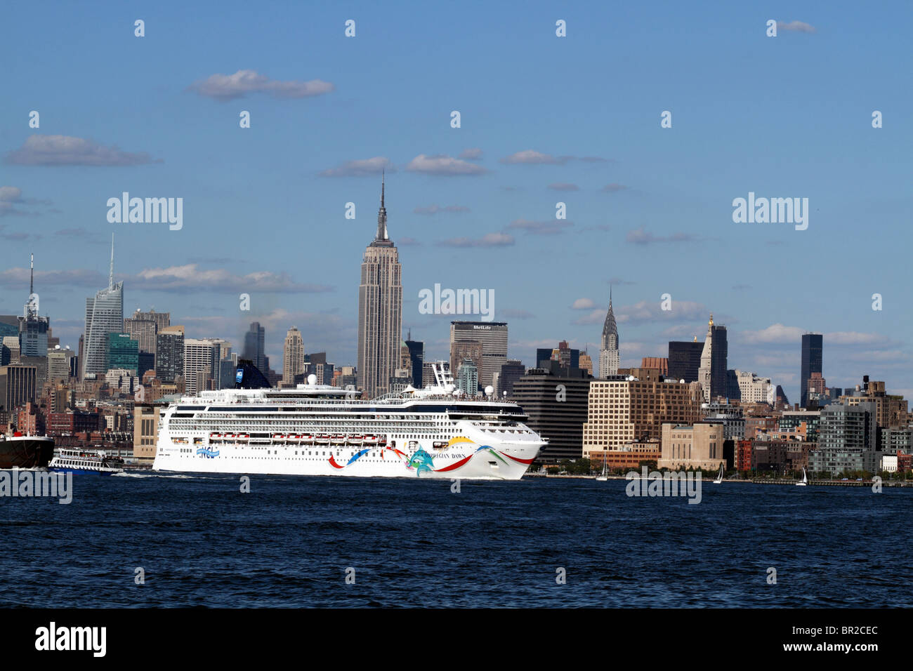 Un navire de croisière, laissant Mid-town Manhattan pour commencer son voyage et passer sous l'Empire State Building. New York City, USA Banque D'Images