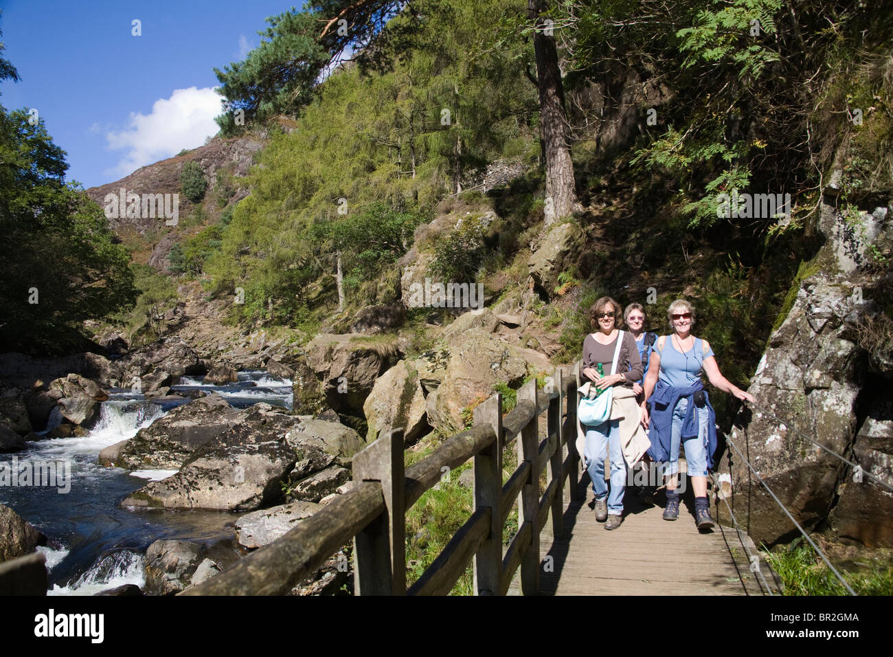 Gwynedd au nord du Pays de Galles Royaume-uni trois femmes traversant un pont sur le chemin à travers le col d'Aberglaslyn une belle marche populaire sur le côté de la rivière Glaslyn Banque D'Images