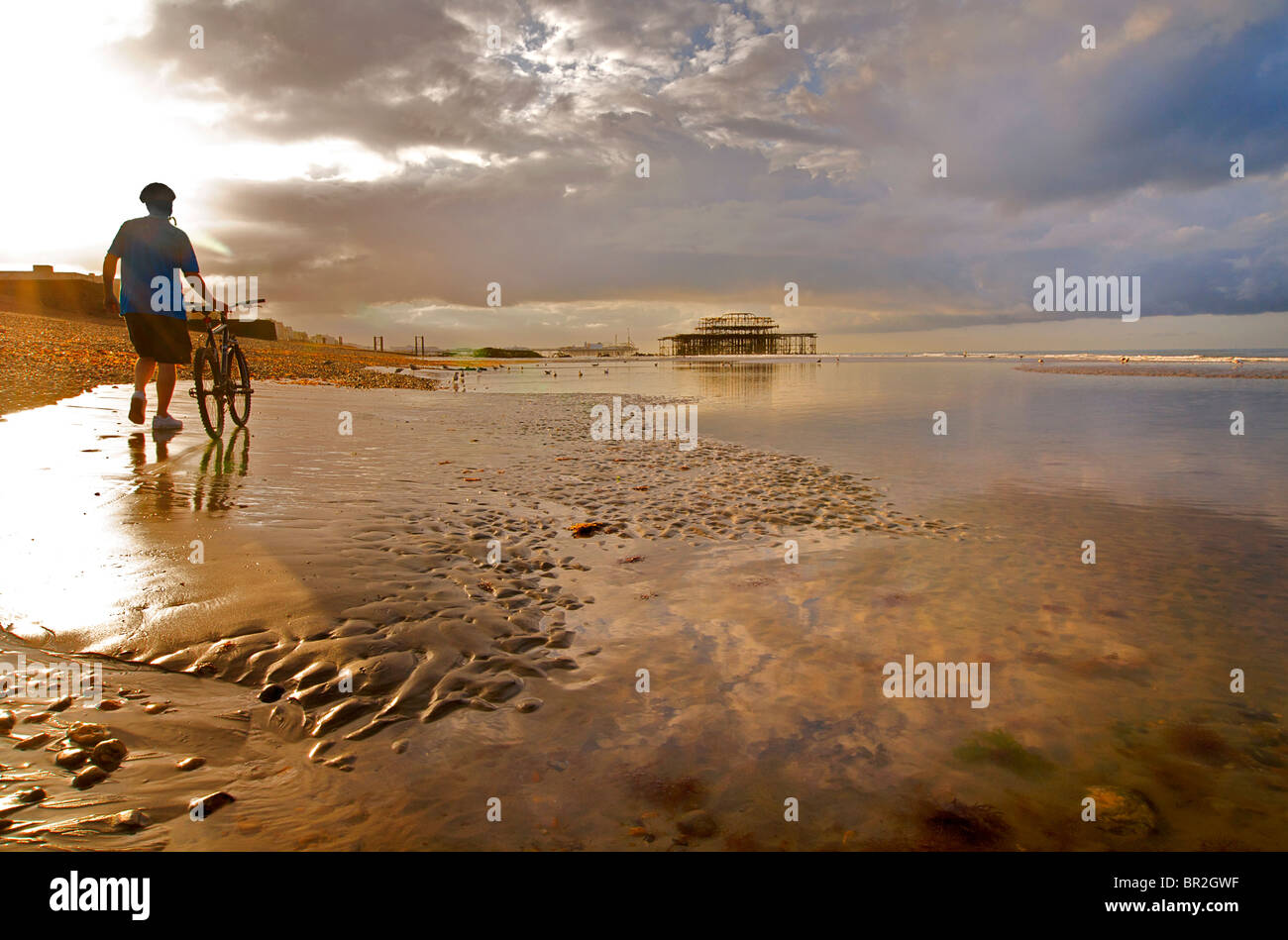 Cycliste avec location sur Hove beach. Vue vers l'abandon de Brighton et le West Pier à marée basse, East Sussex, Angleterre Banque D'Images