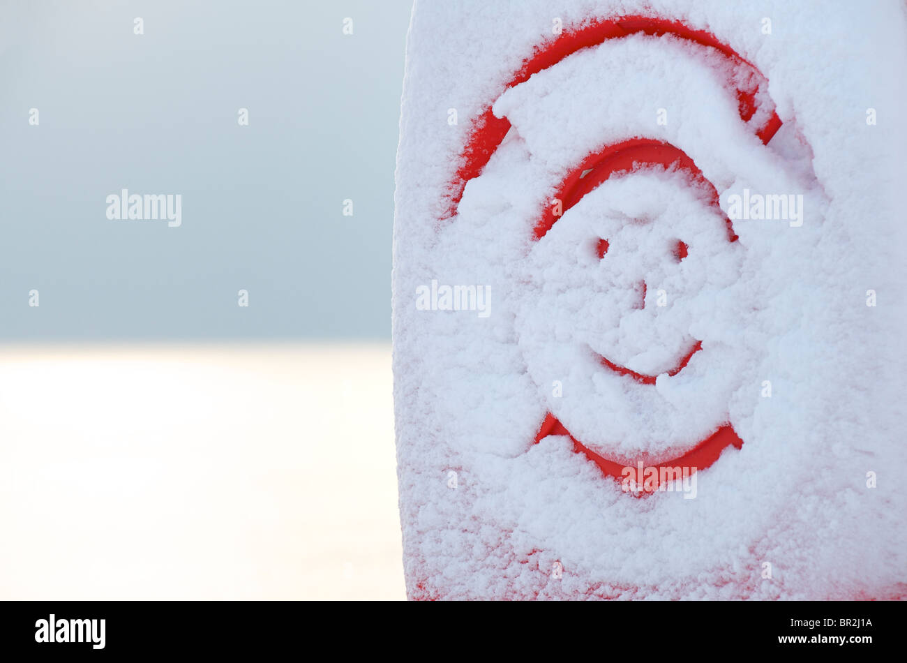 Smiley dessiné dans la neige fraîche sur les appareils de sauvetage à côté de la mer Banque D'Images