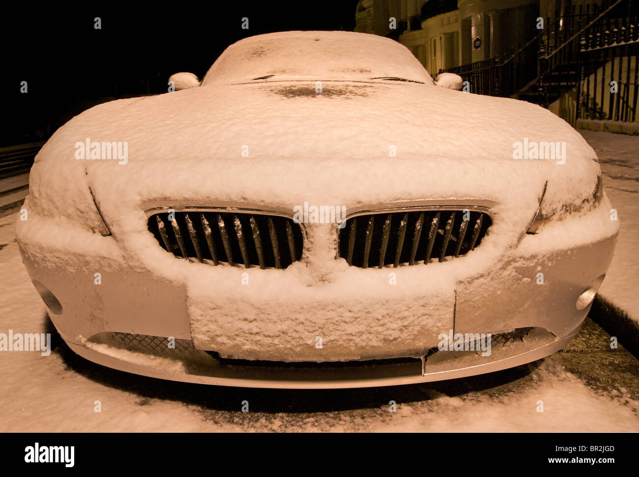 Voiture de sport BMW garée recouverte de neige et éclairé par la lanterne Banque D'Images