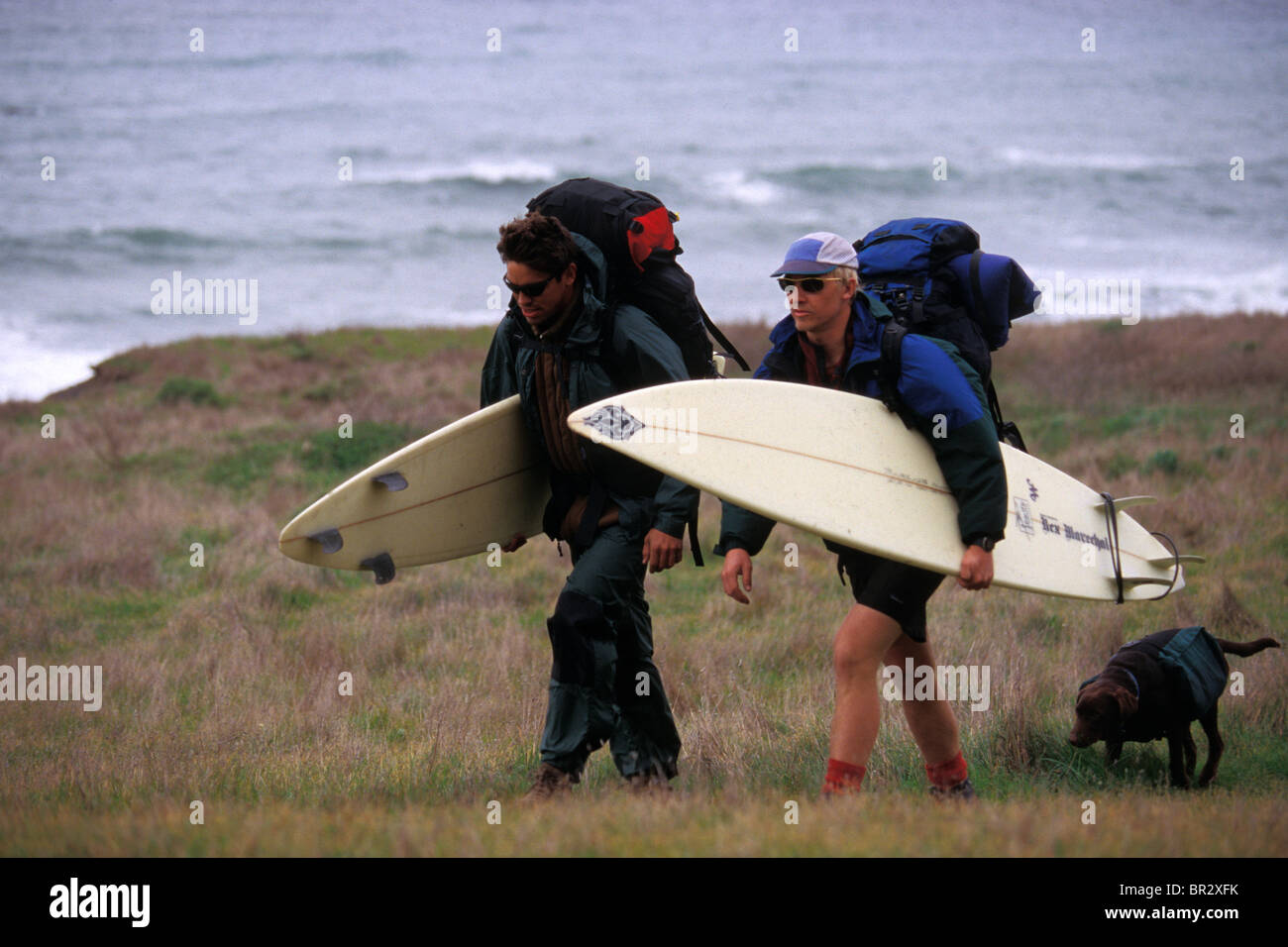 Deux hommes en sac sur la plage avec des planches. Banque D'Images