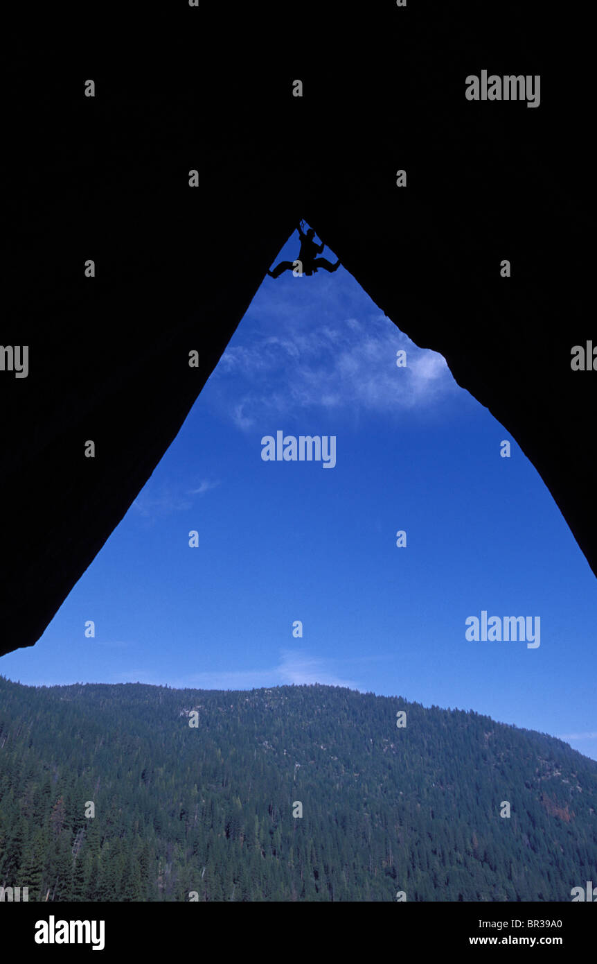 Silhouette d'un grimpeur en haut d'un surplomb. Banque D'Images