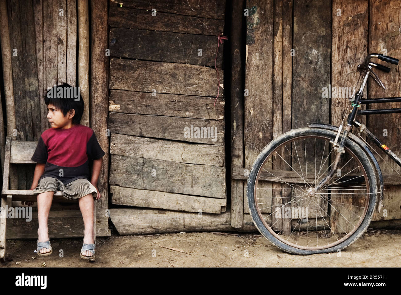 Le fils d'un cultivateur de coca est assis devant son domicile, à l'Amazonie péruvienne. Banque D'Images