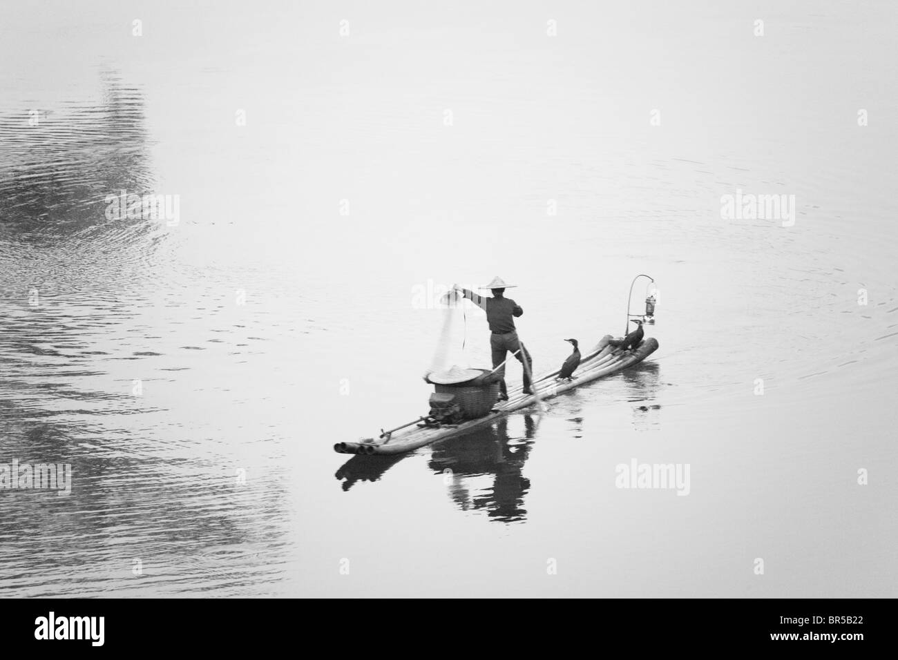 Fisherman casting filet de pêche sur la rivière en radeau de bambou sur Li, Yangshuo, Guangxi, Chine Banque D'Images