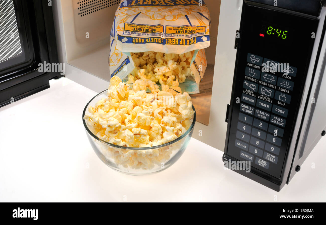 Ouvrir le sachet de pop-corn micro-ondes micro-ondes à l'intérieur secret avec un bol en verre de popcorn cuits à l'avant. Studio Banque D'Images