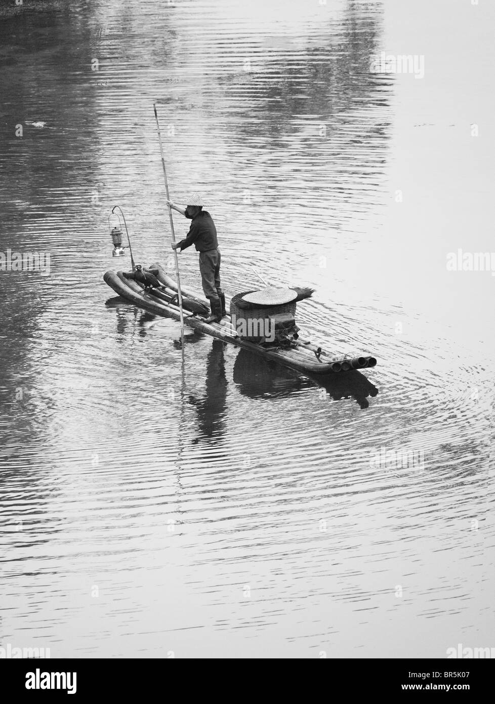 Fisherman casting filet de pêche sur la rivière en radeau de bambou sur Li, Yangshuo, Guangxi, Chine Banque D'Images