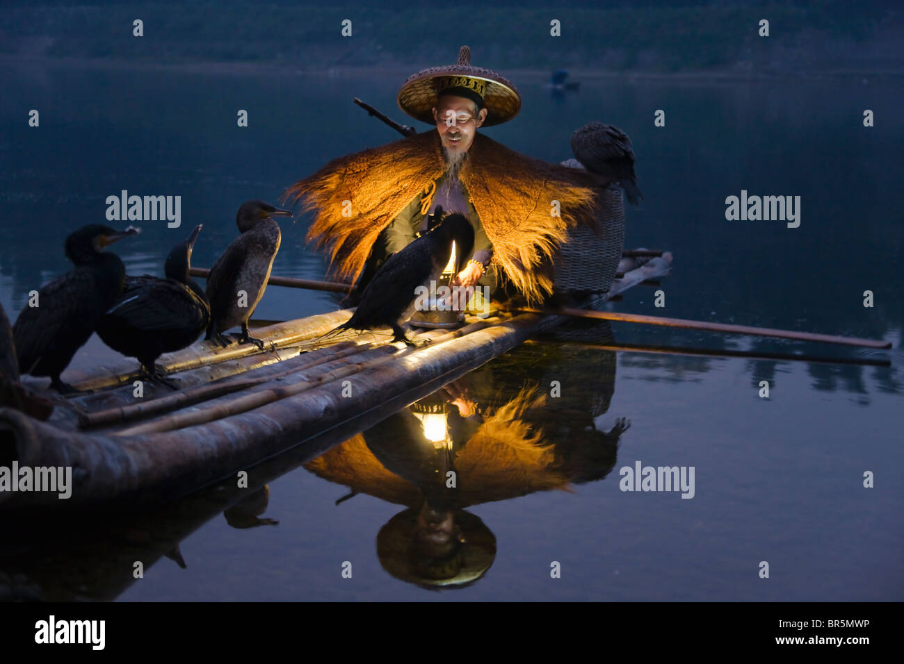 Le port de pêcheur La pêche avec manteau de paille sur les cormorans en radeau de bambou sur la rivière Li au crépuscule, Yangshuo, Guangxi, Chine Banque D'Images