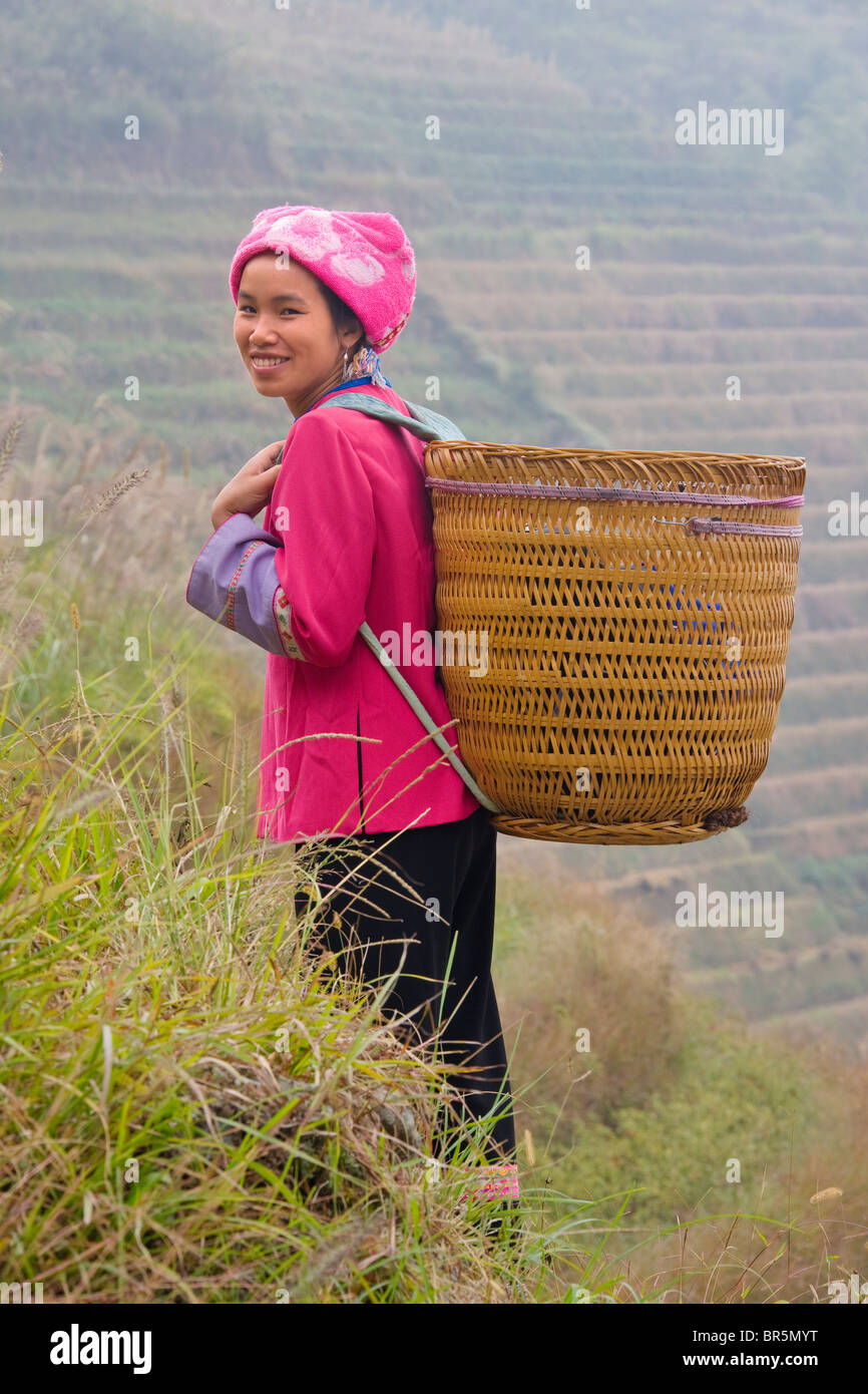 Zhuang girl carrying basket dans la montagne dans la brume, Longsheng, Guangxi, Chine Banque D'Images