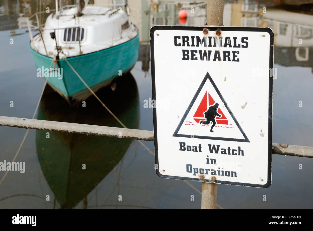 Méfiez-vous des criminels Boatwatch en opération signe à Aberystwyth port avec un yacht amarré derrière. Banque D'Images