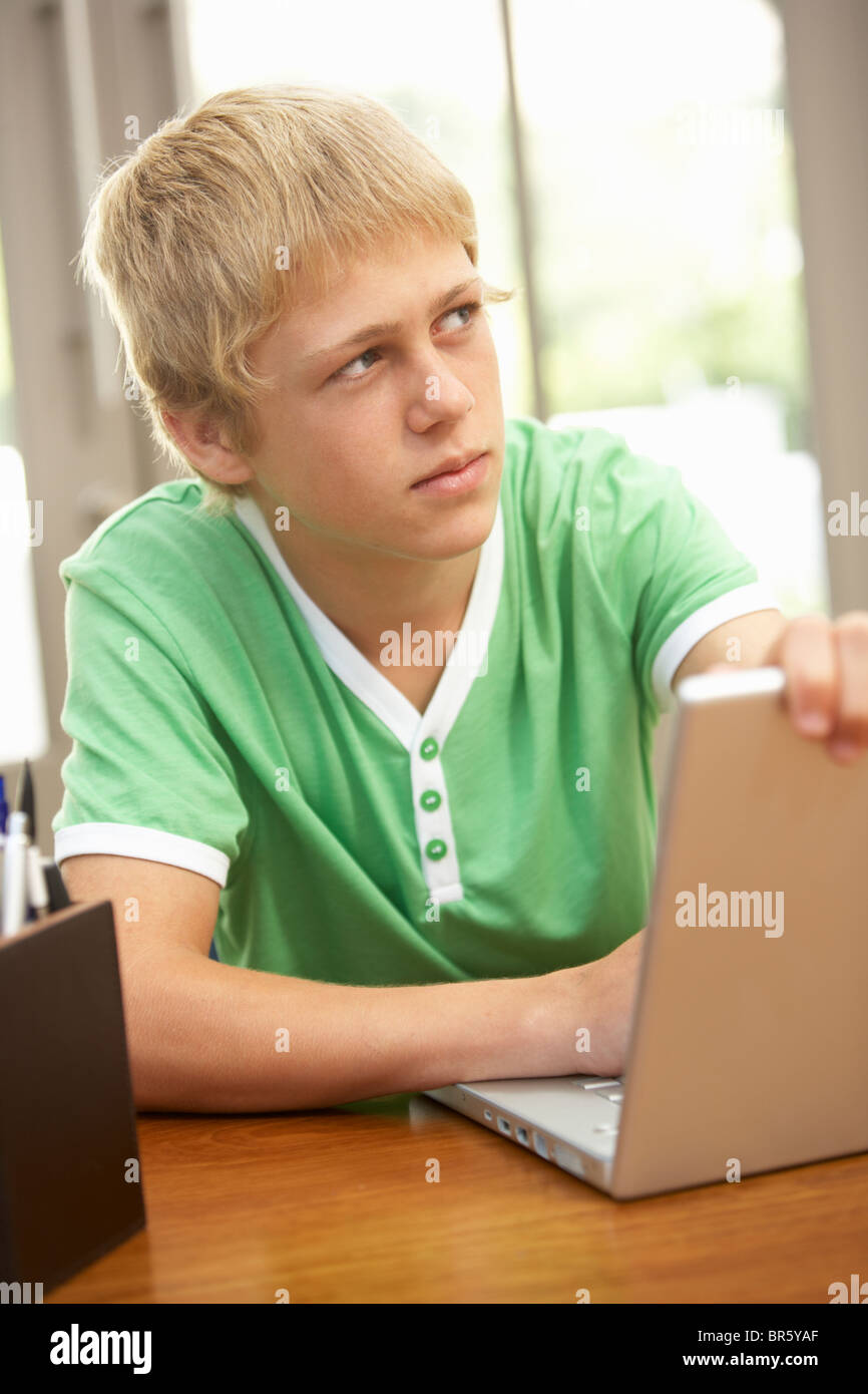 Coupable à Teenage Boy Using Laptop At Home Banque D'Images
