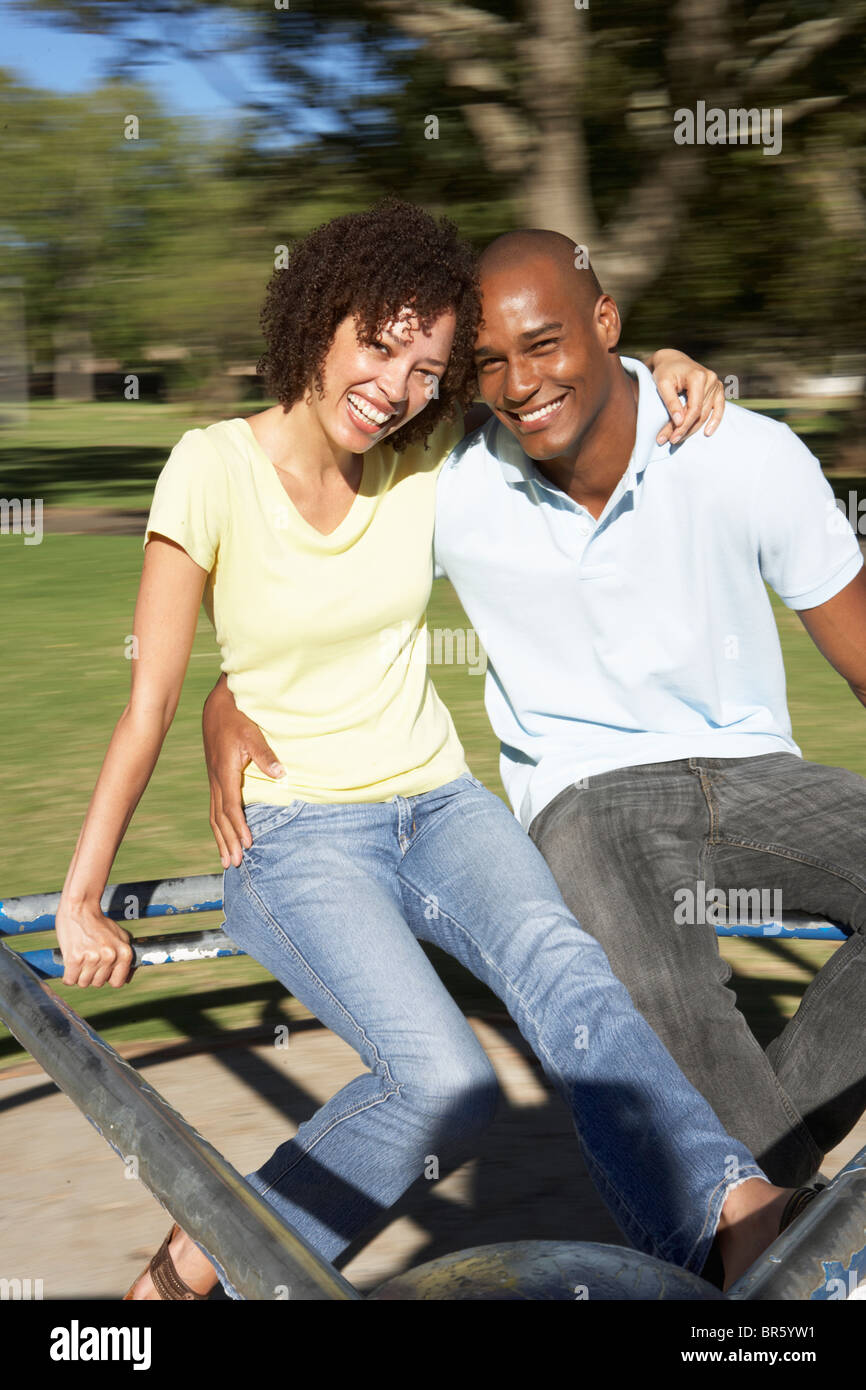 Jeune couple Riding sur rond-point à Park Banque D'Images