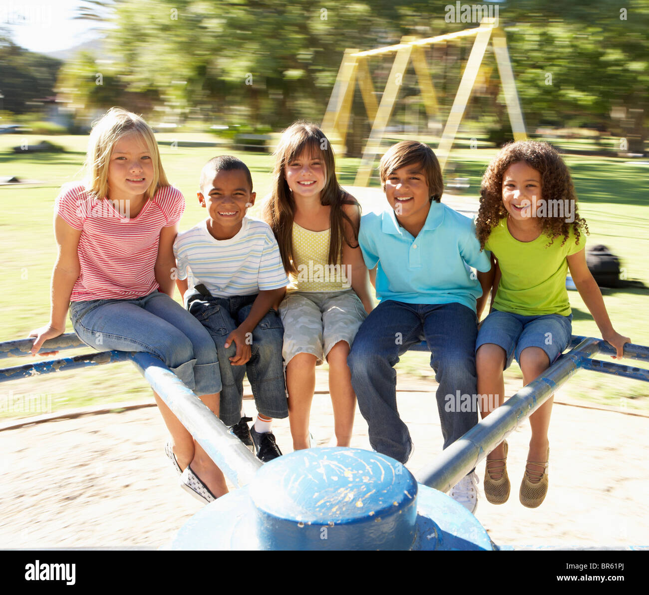 Groupe d'enfants équitation sur rond-point à l'aire de jeux Banque D'Images