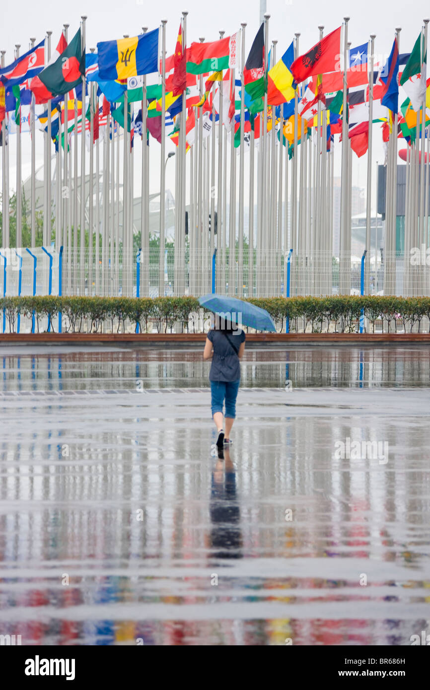 La réflexion de personnes et mâts de drapeau sur le terrain dans la pluie, 2010 Expo, Shanghai, Chine Banque D'Images