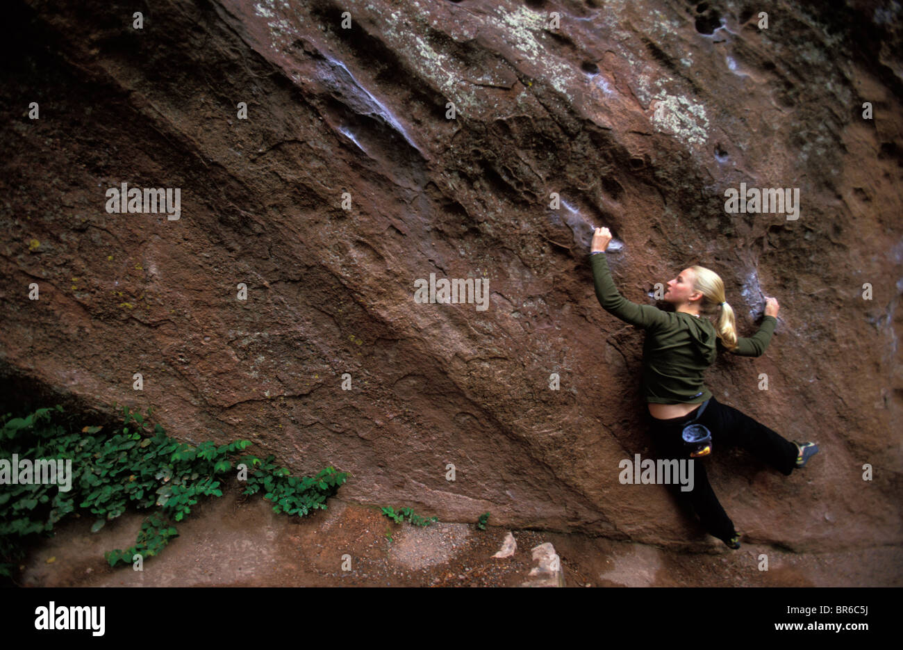 Un female rock climber bouldering sur grès. Banque D'Images