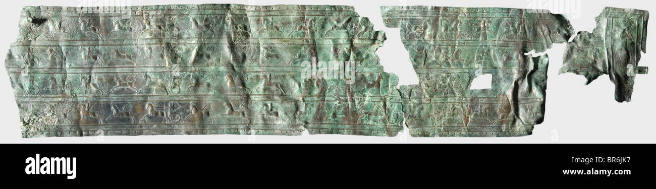 Un fragment d'une ceinture en bronze d'Ourartian, VIIIe siècle avant J.-C. une ceinture en bronze large avec quatre rangées décoratives horizontales avec des représentations de baleines montées, de chars de guerre habités et de bouées de chasse d'arches et de lions. Les quatre rangées séparées par des lignes doubles surélevées entre elles. Trous finement percés le long de la jante. Sur l'extrémité préservée de la ceinture une boucle rivetée pour la bague prenant le laçage en cuir. Longueur : environ 76 cm, largeur : 15,5 cm. Bronze. Patine rouge-brun à vert avec restes de corrosion, déformations anciennes, traces d'exposition au feu. Collection Axel Guttmann, Banque D'Images