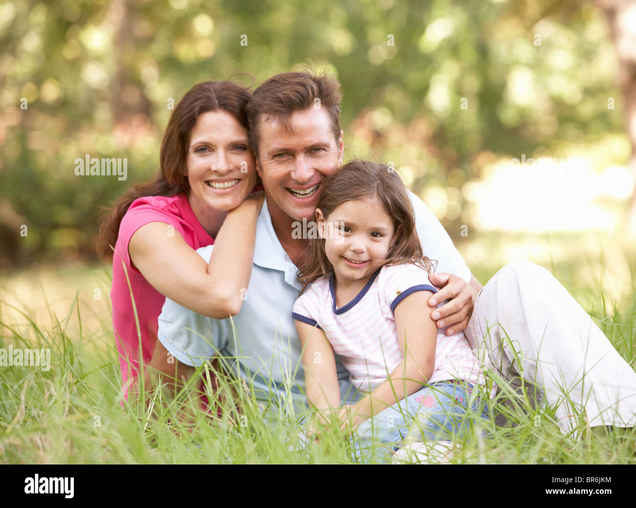 Family Sitting in Long Grass In Park Banque D'Images