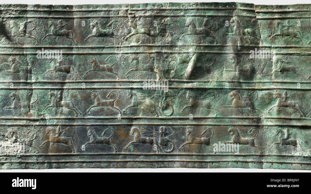 Un fragment d'une ceinture en bronze d'Ourartian, VIIIe siècle avant J.-C. une ceinture en bronze large avec quatre rangées décoratives horizontales avec des représentations de baleines montées, de chars de guerre habités et de bouées de chasse d'arches et de lions. Les quatre rangées séparées par des lignes doubles surélevées entre elles. Trous finement percés le long de la jante. Sur l'extrémité préservée de la ceinture une boucle rivetée pour la bague prenant le laçage en cuir. Longueur : environ 76 cm, largeur : 15,5 cm. Bronze. Patine rouge-brun à vert avec restes de corrosion, déformations anciennes, traces d'exposition au feu. Collection Axel Guttmann, Banque D'Images