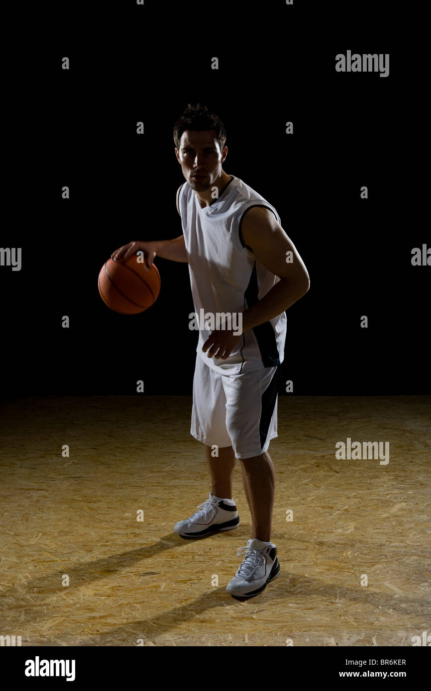 Un joueur de basket-ball dribbler un ballon, portrait, studio shot Banque D'Images