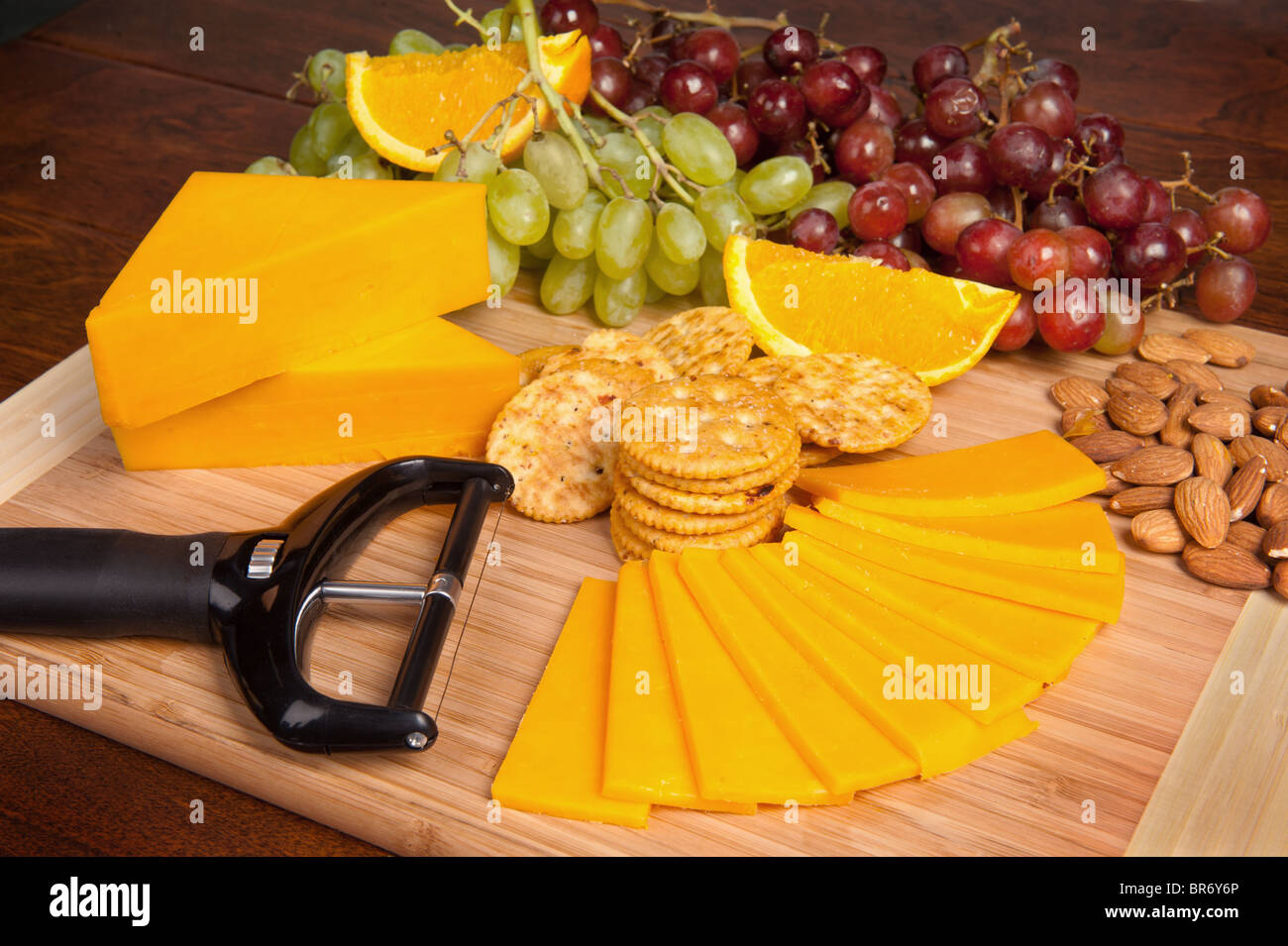 Un plateau de fromage et fruits collations composé de fromage cheddar, les craquelins, les raisins et les oranges. Banque D'Images