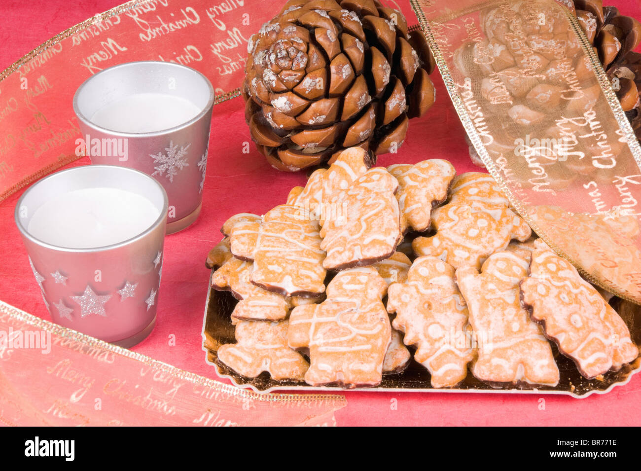 Composition de Noël : gingerbread men, ruban de Noël, des pommes de pin et des bougies. Studio shot sur fond rouge Banque D'Images
