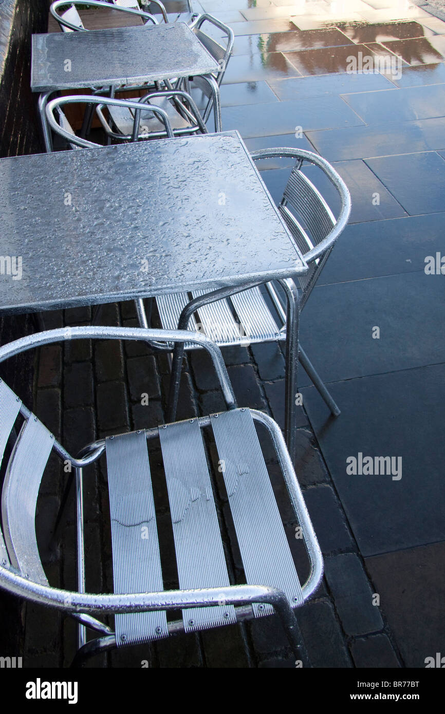 Wet aluminium aluminium tables basses et chaises sur une chaussée mouillée trottoir Banque D'Images