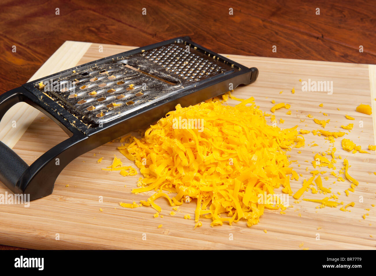 Le fromage fraîchement râpé sur une planche à découper assis sur une table en bois. Banque D'Images