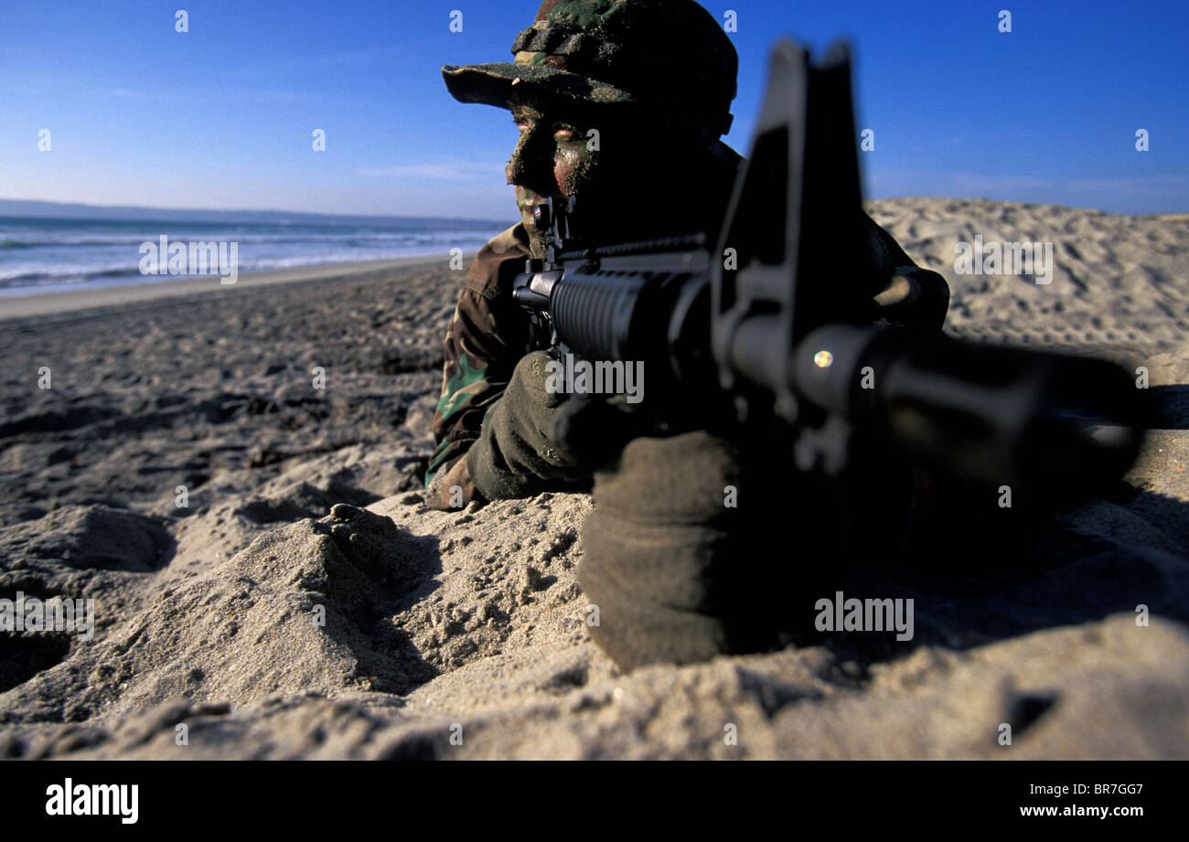 Navy Seal dans la formation portant sur la plage avec une arme à feu à San Diego en Californie. Banque D'Images