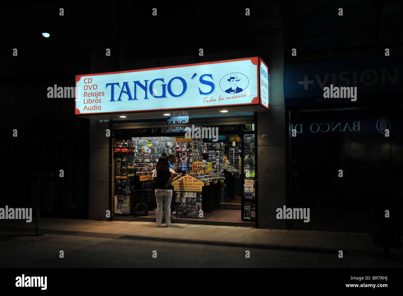 Photo de nuit d'hommes et de femmes consommateurs à la recherche de dvd dans une petite boutique de musique avant-, nommé 'Tango', Lavalle, Buenos Aires Banque D'Images