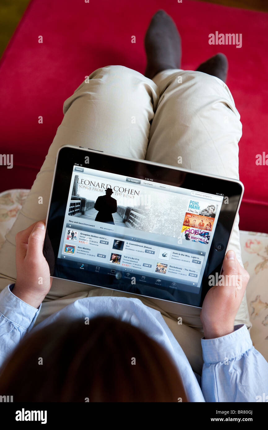 Femme à l'aide de l'ordinateur tablette iPad pour parcourir l'iTunes music store en ligne numérique Banque D'Images