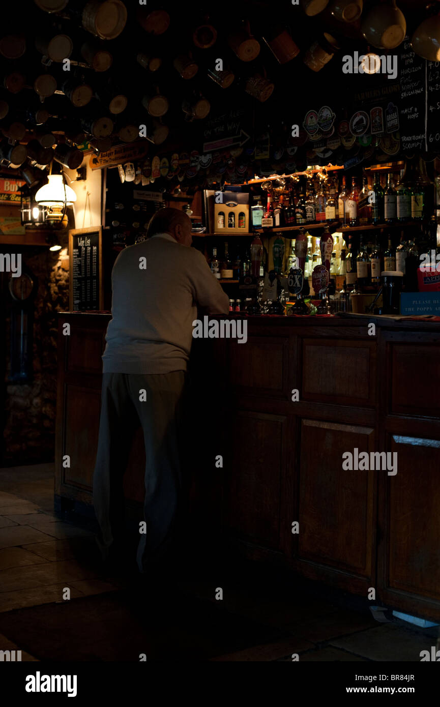 Un homme âgé se tient au comptoir des îles Falkland Arms Public House dans Great Tew, Oxfordshire Banque D'Images