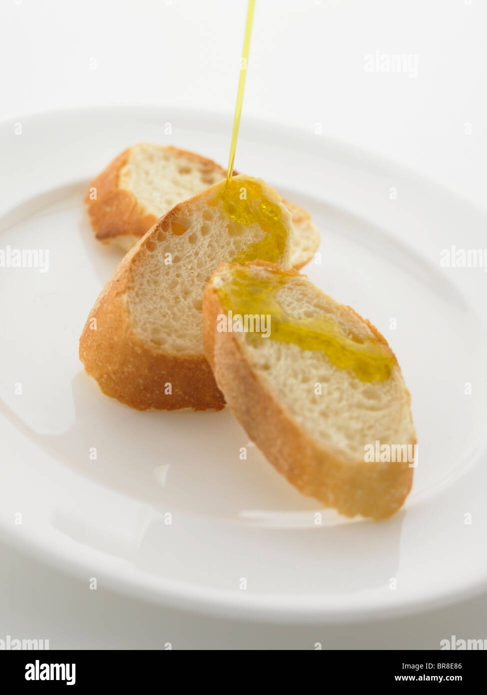 On verse de l'huile d'olive sur baguette Banque D'Images