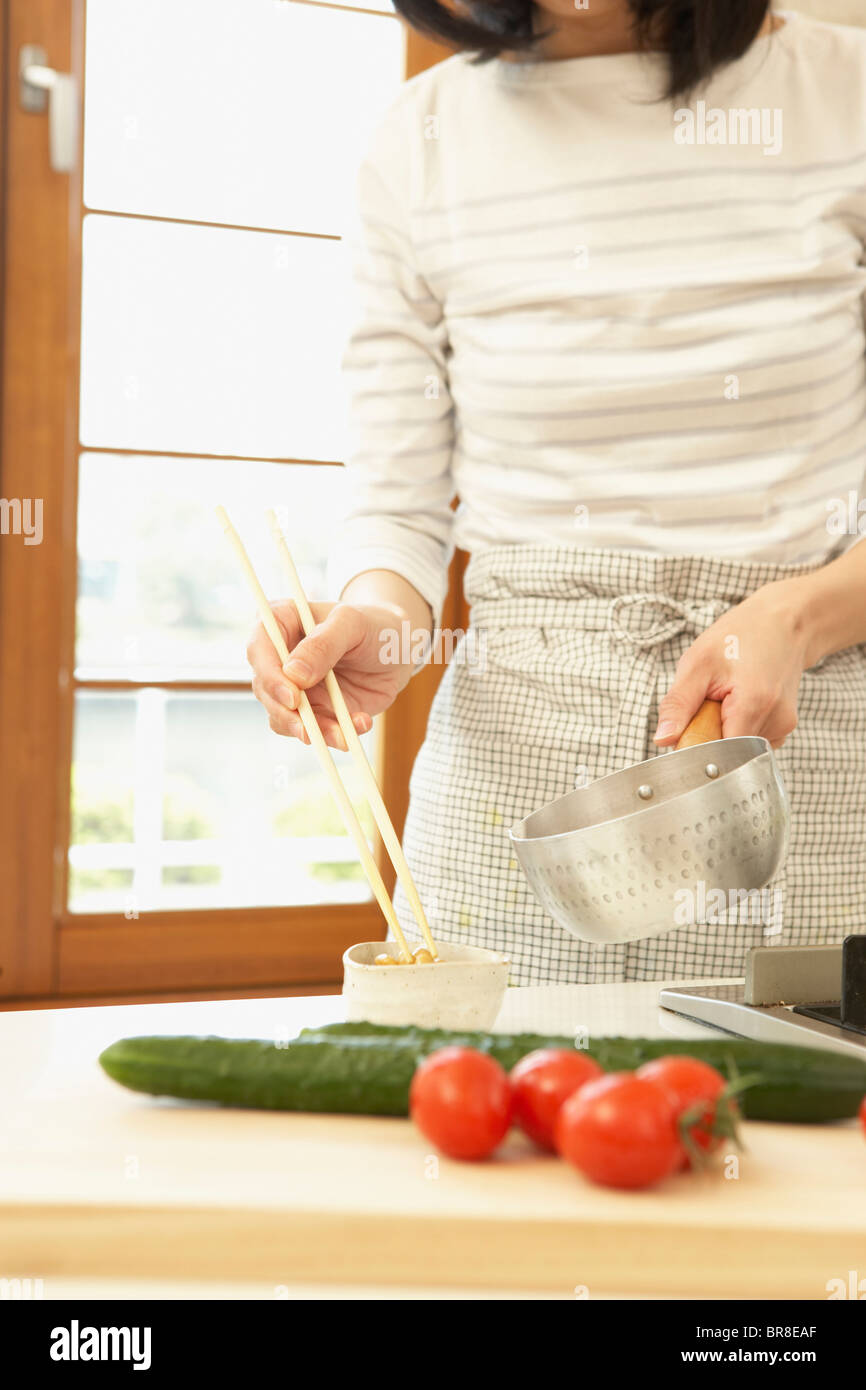 Femme dans la cuisine, tenant des baguettes et pan Banque D'Images