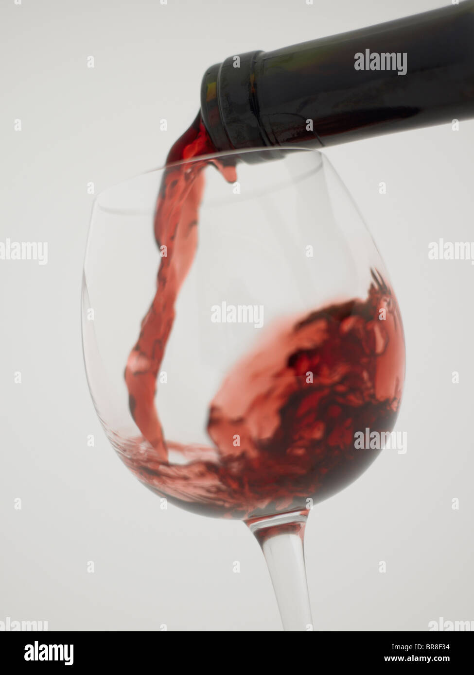 Vin rouge verser dans grass, Close up, fond blanc Banque D'Images