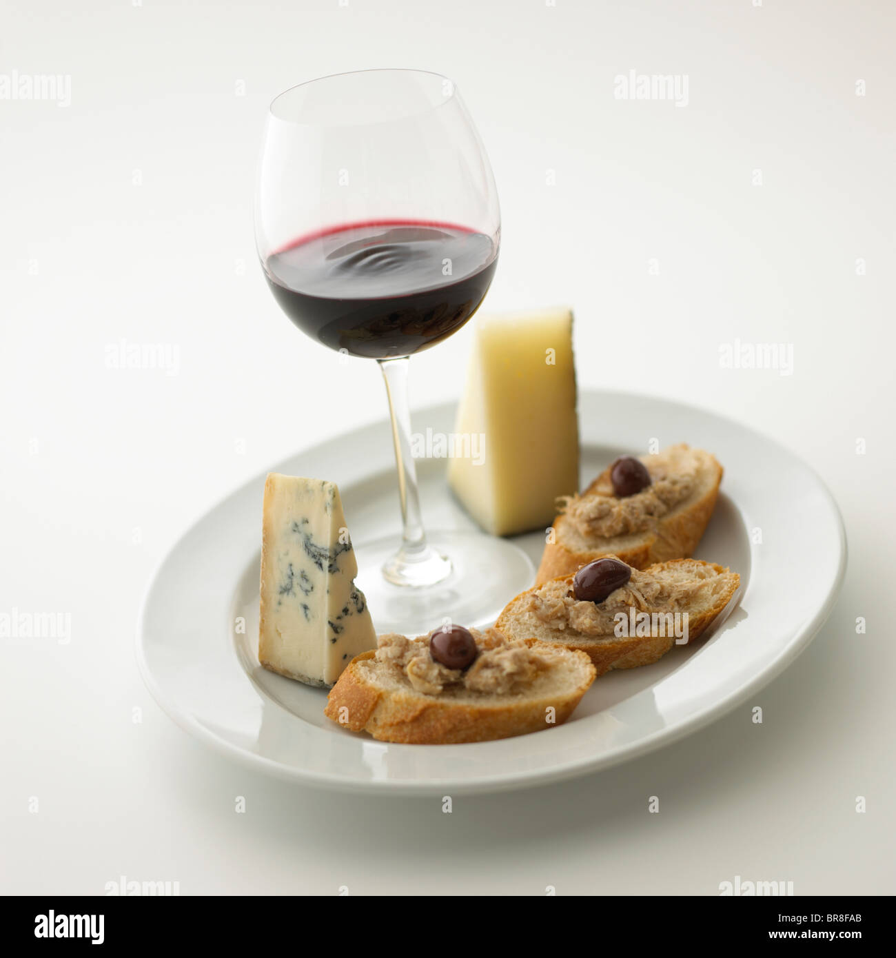 Verre de vin rouge et une assiette de fromage et de pain, fond blanc Banque D'Images